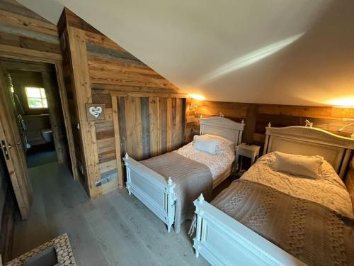 two beds in a room with wooden walls at Chalet Beaune - Charming and Stylish Chalet in Les Gets in Les Gets