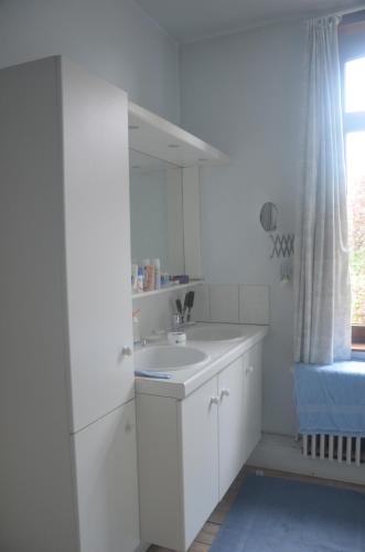 a white bathroom with a sink and a window at Beaux Temps b&b in Aalter