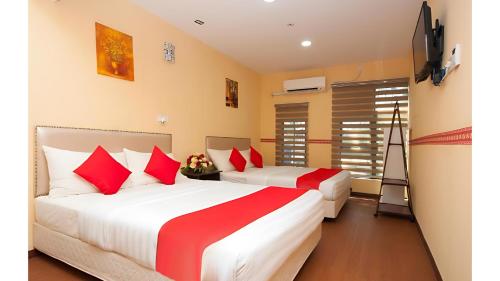 duas camas num quarto com lençóis vermelhos e brancos em Bintang Square Hotel em Kubang Kerian