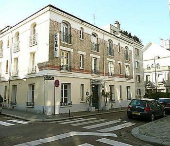 un gran edificio blanco con coches estacionados frente a él en Hôtel Le Home Saint Louis, en Versalles