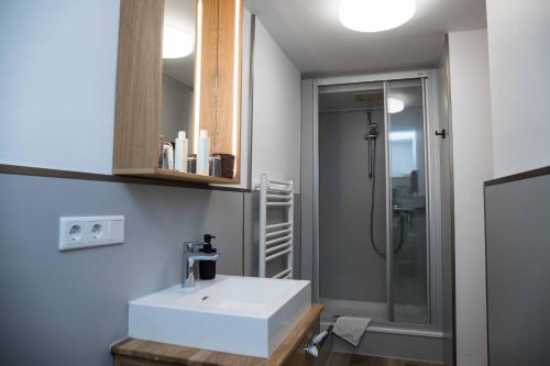a bathroom with a white sink and a shower at Appartementhaus Westend in Norderney