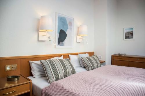 a hotel room with two beds and two lamps at Appartementhaus Westend in Norderney