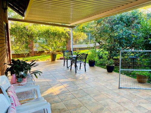 a patio with a table and chairs on it at Rondeletia Cottage Guesthouse - premium self catering in Winston Park