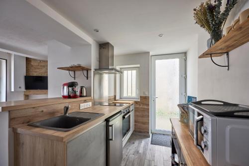 une cuisine avec un évier et une cuisinière dans l'établissement La Maison du Pêcheur - A 250 m de la plage, à Saint-Aubin-sur-Mer