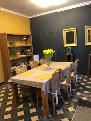 uma sala de jantar com uma mesa com flores amarelas em Beaux Temps b&b em Aalter