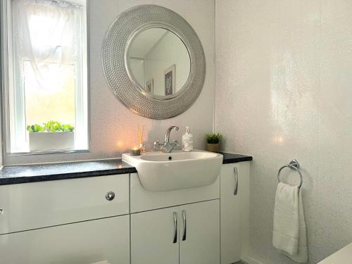 W białej łazience znajduje się umywalka i lustro. w obiekcie Duchess House 1- Spacious & Modern 3BR GF w mieście Colchester