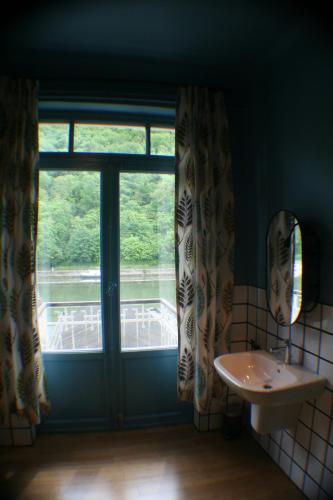 een badkamer met een raam en een wastafel naast bij Echappée mosane in Waulsort