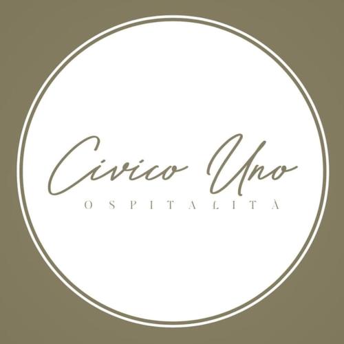 a white circle with a silver cursive logo at Civico Uno Appartamento in Torgiano