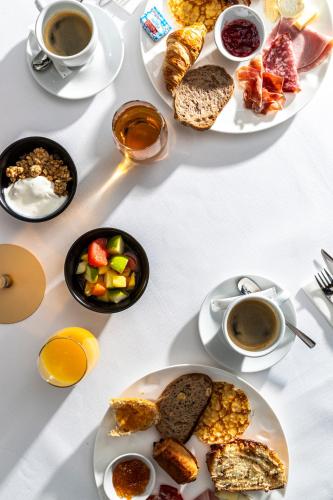 a table with plates of food and cups of coffee at Hôtel Restaurant Relais De La Poste - Strasbourg Nord in La Wantzenau