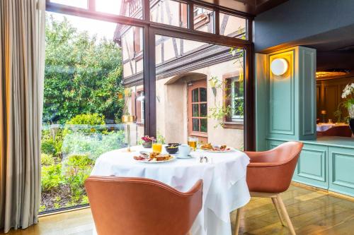 a dining room with a table and chairs and a window at Hôtel Restaurant Relais De La Poste - Strasbourg Nord in La Wantzenau