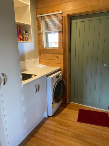 基督城的住宿－The Log Cottage，厨房配有洗衣机、洗衣机和烘干机。