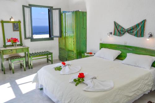 a bedroom with a white bed with red flowers on it at Hotel Finiki View in Foiníkion