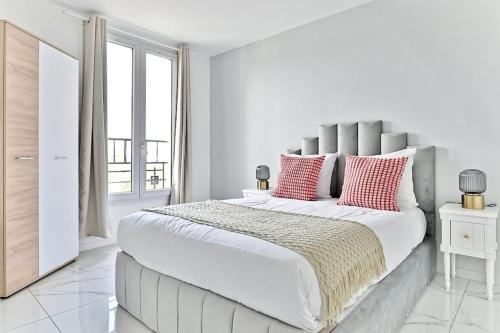 ein weißes Schlafzimmer mit einem großen Bett mit roten Kissen in der Unterkunft Magnifique 2 pieces aux portes de Paris in Gagny