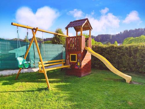 a small playground with a slide in a yard at Chata u pltníka Paľka in Podbiel
