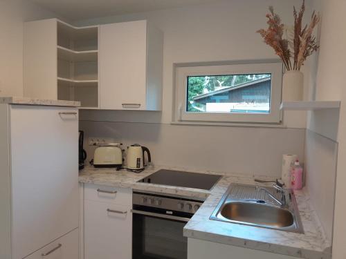 a white kitchen with a sink and a window at Matys Landhausperle an der Müritz in Röbel