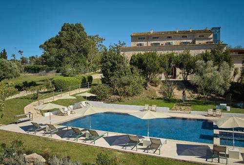 een zwembad met stoelen en een gebouw op de achtergrond bij Es Figueral Nou Hotel Rural & Spa - Adults Only - Over 12 in Montuiri