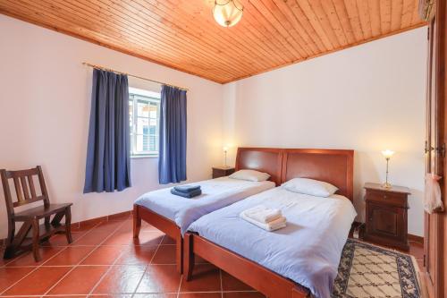 een slaapkamer met 2 bedden, een stoel en een raam bij Charming granite cottage in beautiful surroundings in Casal Diz