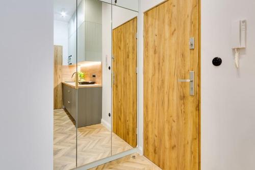 a glass shower in a bathroom with a wooden wall at Więzienna Old Town in Wrocław