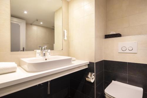 a bathroom with a sink and a toilet and a mirror at Hôtel Restaurant Relais De La Poste - Strasbourg Nord in La Wantzenau