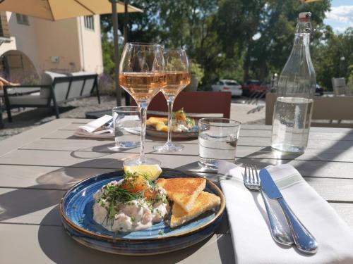 a table with a plate of food and two glasses of wine at Hotell Kristina in Sigtuna