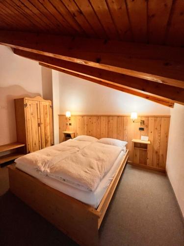 Tartano的住宿－阿爾伯格格蘭巴依塔酒店，卧室设有一张大床,卧室设有木墙