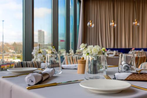 a table with plates and vases with flowers on it at Warsaw Presidential Hotel in Warsaw