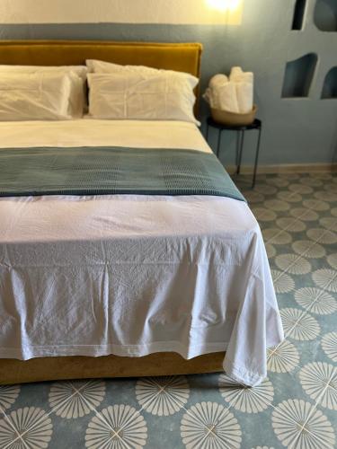 a bedroom with a bed with white sheets and a floor at GarganoMareBorghi ospitalità diffusa in Vico del Gargano