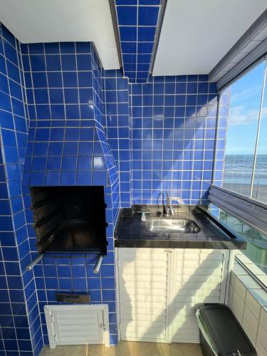 Apto Frente a Praia, Completo في Solemar: حمام من البلاط الأزرق مع حوض ونافذة