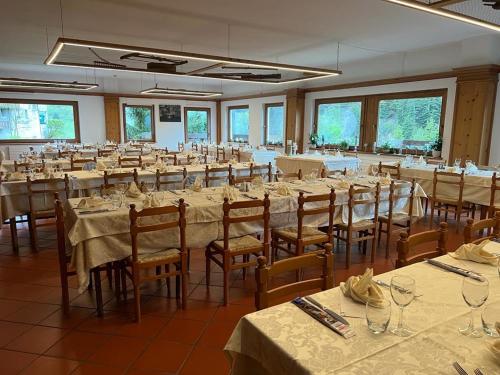 een grote kamer met tafels en stoelen met witte tafelkleden bij Albergo La Gran Baita in Tartano
