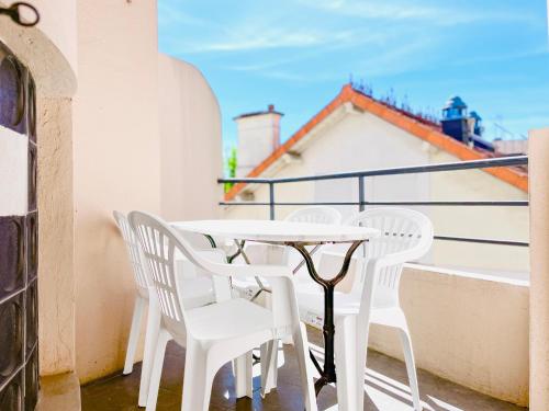 une table blanche et des chaises sur un balcon dans l'établissement Le Boëste - Magnifique logement lumineux, à Cannes