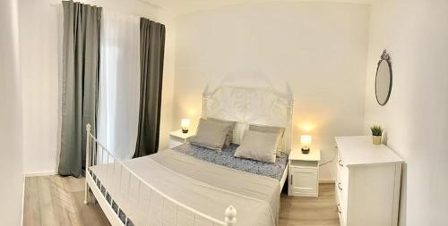 een witte slaapkamer met een wit bed en 2 nachtkastjes bij Apartmani Kalos in Vela Luka