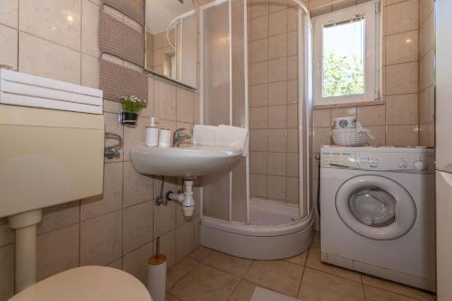a bathroom with a sink and a washing machine at Charming holiday home Little House in Povljana