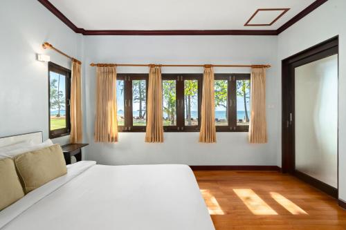 Koh Chang Longstay Resort في كو تشانغ: غرفة نوم بسرير ابيض ونوافذ