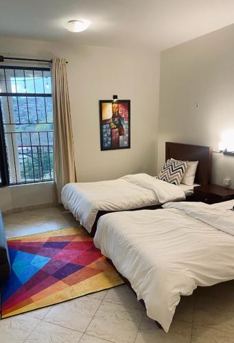 two beds in a room with a rainbow rug at Khyz Views Executive Suite with Private Terrace in Murree