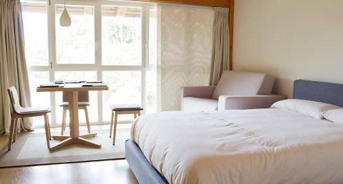 a bedroom with a bed and a table and a window at Ureta Landa Gaztelugatxe in Bakio