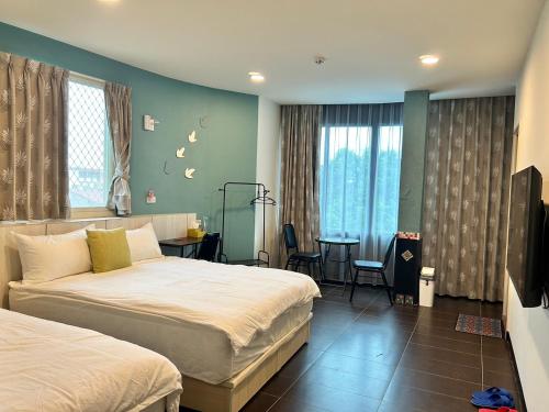 a hotel room with two beds and a table at 玩轉金門民宿2館-樂遊小鎮民宿 in Jincheng