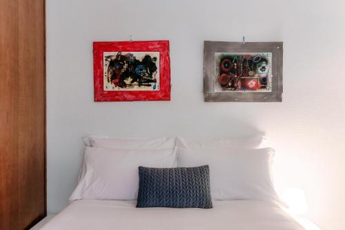 a bedroom with three pictures above a white bed at Casa In Contrada by Quokka 360 - Village life and lake in Bissone