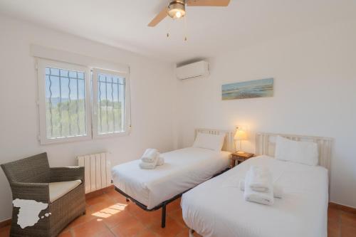 ベニッサにあるCostaBlancaDreams Villa Colina in Benissaのベッド2台、椅子、窓が備わる客室です。