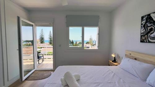 Un dormitorio con una cama blanca y un balcón. en Mshome Beach Haven, en Torre de Benagalbón