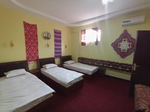 a room with two beds and a window and two windows at Khiva Saodat Guest House in Khiva