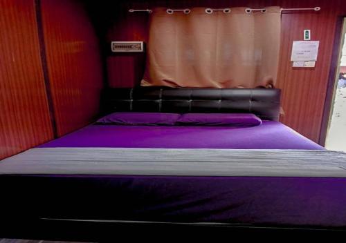 a bedroom with a bed with purple sheets and a curtain at AISHAH GUEST HOUSE in Perhentian Island
