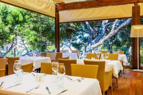 a restaurant with white tables and yellow chairs at VIVA Cala Mesquida Resort & Spa in Cala Mesquida