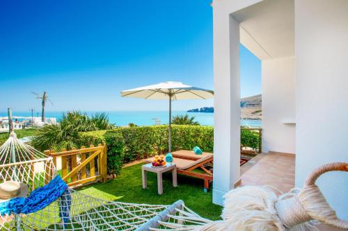 a patio with a hammock and a view of the ocean at VIVA Cala Mesquida Resort & Spa in Cala Mesquida