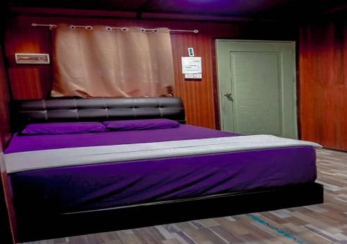 a bedroom with a bed with purple sheets and a door at AISHAH GUEST HOUSE in Perhentian Island