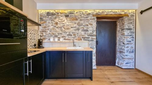 une cuisine avec des placards bleus et un mur en pierre dans l'établissement Le Relais de Diligence Balnéo & Sauna, à Salsigne