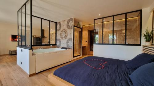 une chambre avec un grand lit et une baignoire dans l'établissement Le Relais de Diligence Balnéo & Sauna, à Salsigne