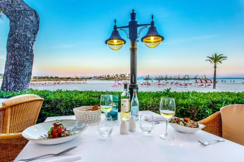 einen Tisch mit Weingläsern und einen Tisch mit Strandblick in der Unterkunft VIVA Golf Adults Only 18+ in Port d'Alcúdia