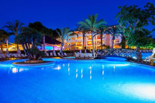 a pool at night with a hotel in the background at VIVA Blue & Spa in Playa de Muro