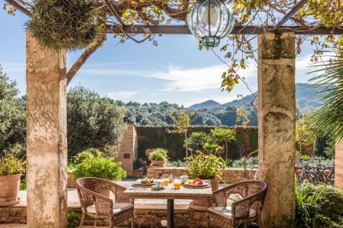 a table and chairs on a patio with mountains in the background at Predi Son Jaumell Hotel Rural in Capdepera