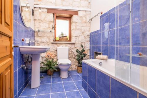 een blauw betegelde badkamer met een toilet en een wastafel bij Villa Artemisia by Villa Plus in Ágios Nikólaos